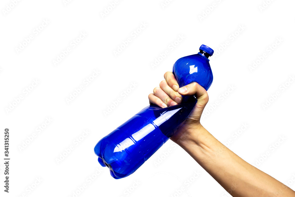 Concept of stop plastic pollution, global warming, recycling plastic, plastic free. Hand tightly squeezes an empty blue plastic bottle in a sign of protest. White background with an isolated subject