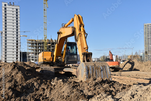 Excavators during earthmoving at construction site. Backhoe dig ground for the construction of foundation and laying sewer pipes district heating. Earth-moving heavy equipment on road works