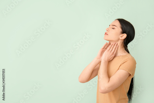 Foto Young woman with thyroid gland problem on color background