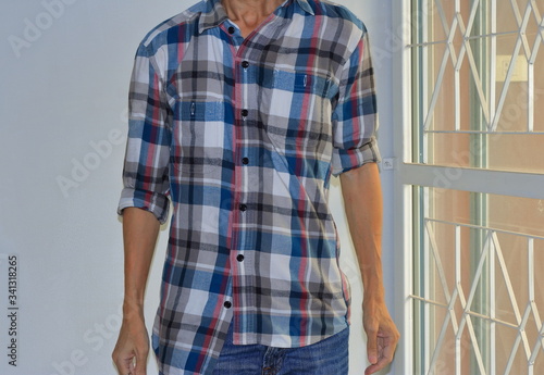 Man wearing buttoned wrong and rolled up sleeves plaid shirt, mistake or intend to break the rule  photo