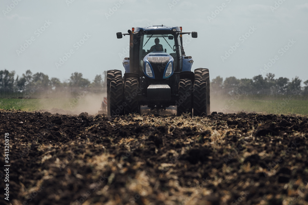 Fototapeta premium big blue tractor with big wheels in a field in summer at an agricultural exhibition