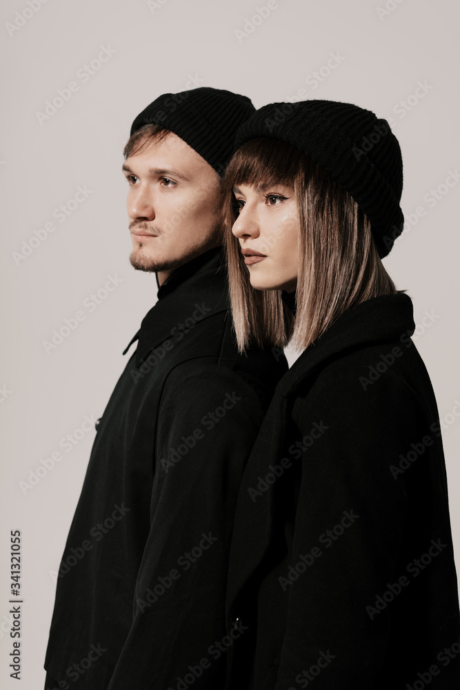 Portrait of urban fashion beautiful couple in black clothes posing over white background together. Close up fashion portrait of stylish young couple pretty woman and handsome man