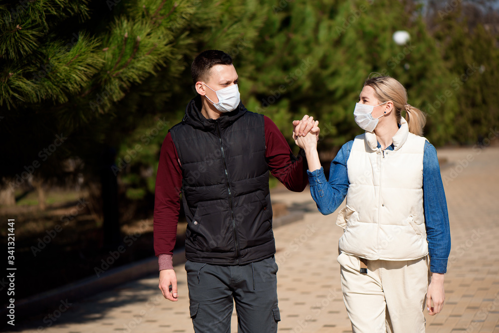 Friends in face masks walk in the park for fear of becoming infected with coronavirus. Friends in face masks walk in the park for fear of becoming infected with coronavirus.