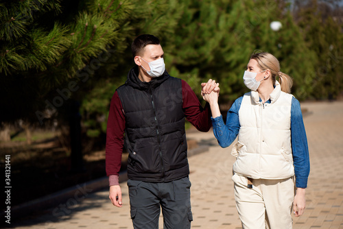 Friends in face masks walk in the park for fear of becoming infected with coronavirus.