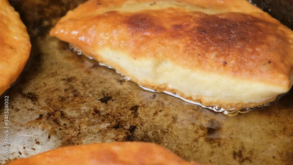 Traditional European cuisine. Pies are fried in hot oil on an iron pan. Traditional European cuisine. Pies are fried in hot oil on an iron pan.