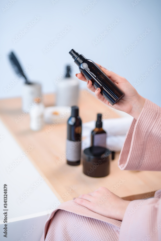 The girl holds a hair care product. A beautiful bottle of a girl in her hands. means of hygiene. cosmetics. studio The girl holds a hair care product. A beautiful bottle of a girl in her hands. means of hygiene. cosmetics. studio