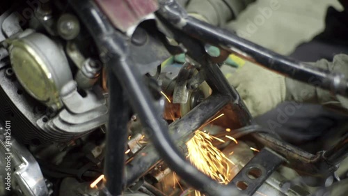 mechanic use angle grinder machine on motorcycle metal frame