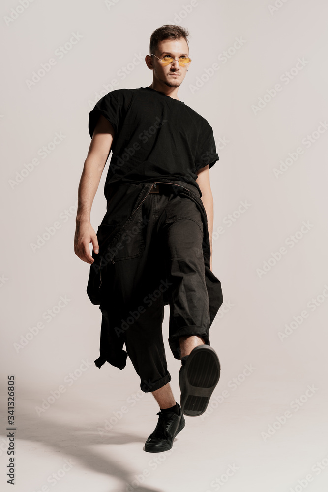 I did it. Full length of confident young man in black clothes jumping, walking against white background I did it. Full length of confident young man in black clothes jumping, walking against white background