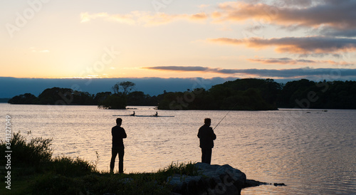 Silhouettes of men fishing on the lakes of Killarney national park at sunset