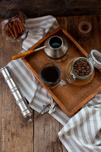 A cup of coffee on a wooden tray. Turk and coffee beans. Cook breakfast at home. Still life with a drink in a glass. Ground coffee, brew and prepare a tonic morning drink.