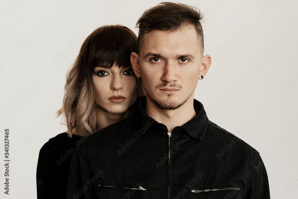 Portrait of urban fashion beautiful couple in black clothes posing over white background together. Close up fashion portrait of stylish young couple