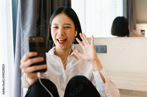 Beautiful asian female in white shirt calling mobile phone while working on bed. work from home concept.
