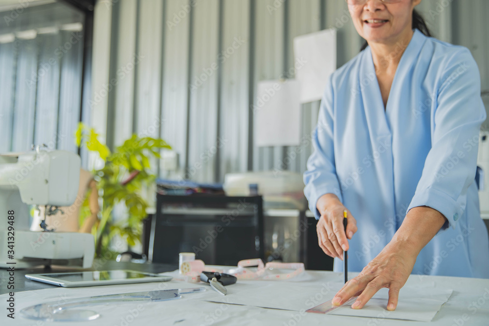 Beautiful fashion old woman designer standing in studio. Old woman fashion designer working in studio Beautiful fashion old woman designer standing in studio. Old woman fashion designer working in studio