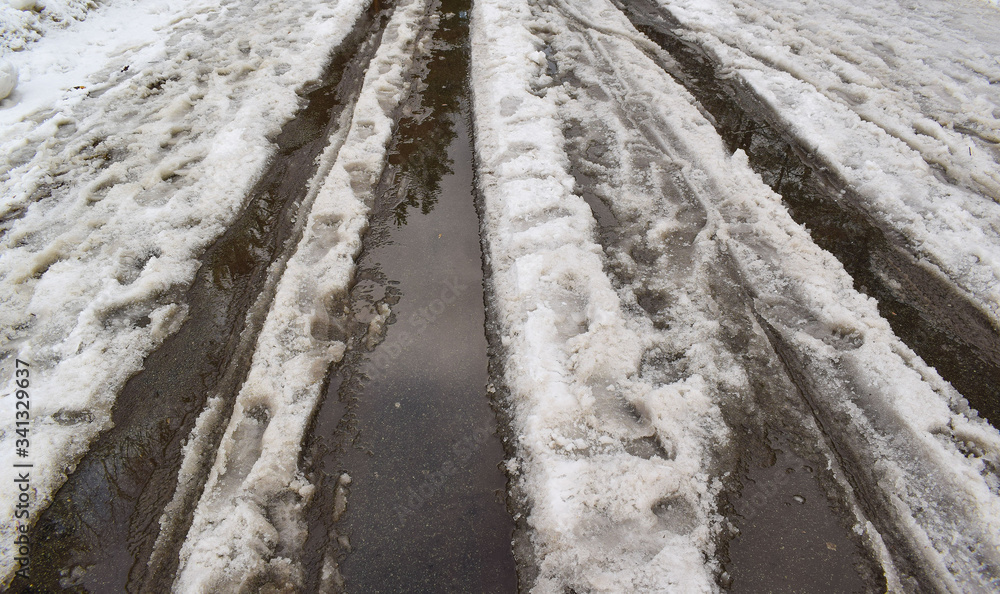 Snow is melting on the road. Spring came. Puddles and ice. Snow is melting on the road. Spring came. Puddles and ice.