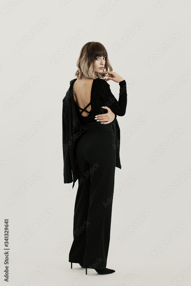 Fototapeta premium Full length portrait, beautiful woman with attitude wearing black clothes posing on white background looking at the camera
