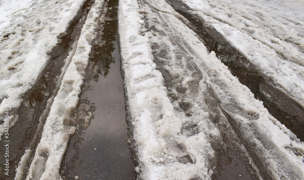 Snow is melting on the road. Spring came. Puddles and ice. Snow is melting on the road. Spring came. Puddles and ice.