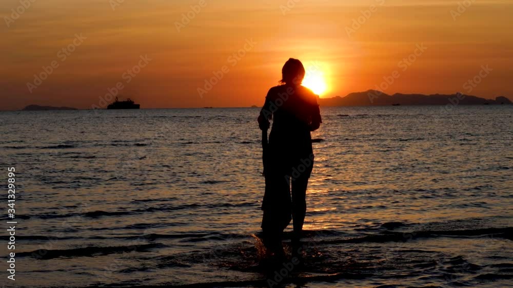 Silhouettes of mother and daughter jump on sand sea coast. Dramatic Sunset with Gold wave at beach. Concept of friendship, love and family forever and of summer vacation Silhouettes of mother and daughter jump on sand sea coast. Dramatic Sunset with Gold wave at beach. Concept of friendship, love and family forever and of summer vacation