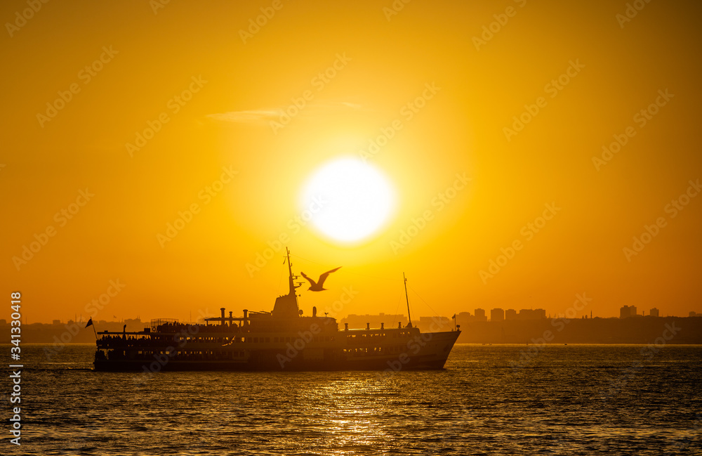 Ferry sails through the Bosphorus Strait in Istanbul, Turkey, during sunset