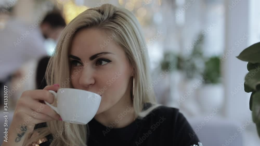 Pretty woman drinking tea in cafe looking at camera Pretty woman drinking tea in cafe looking at camera