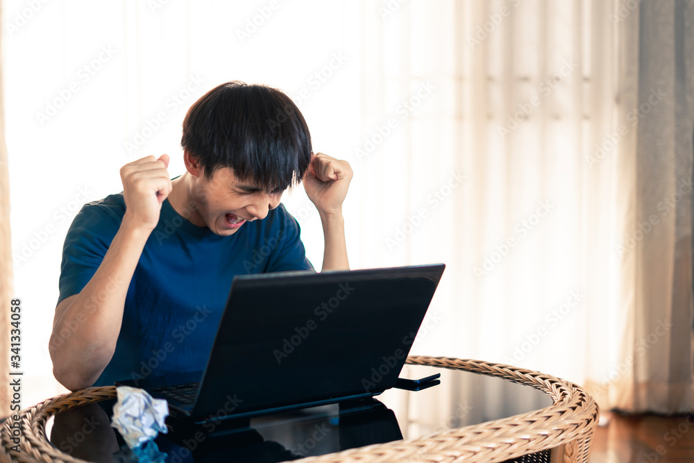 Angry crazy man hand fists up with yelled madly and crumpling paper on table with work on laptop computer in the room, Work from home concept. Angry crazy man hand fists up with yelled madly and crumpling paper on table with work on laptop computer in the room, Work from home concept.