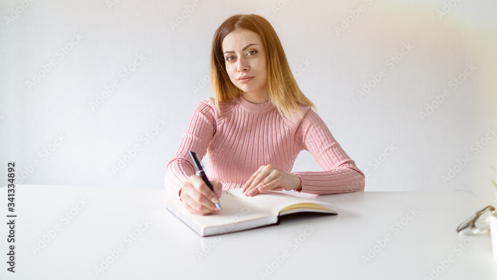 European girl looking at the camera. beautiful student is working at home. self isolation concept European girl looking at the camera. beautiful student is working at home. self isolation concept