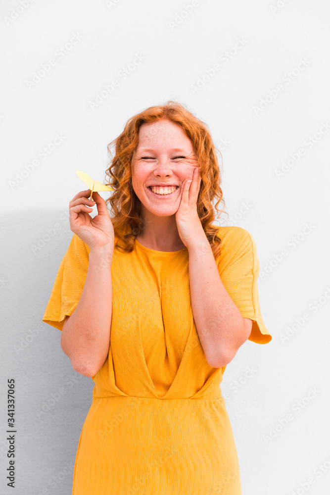 Happy girl holding paper plane wearing yellow dress Happy girl holding paper plane wearing yellow dress