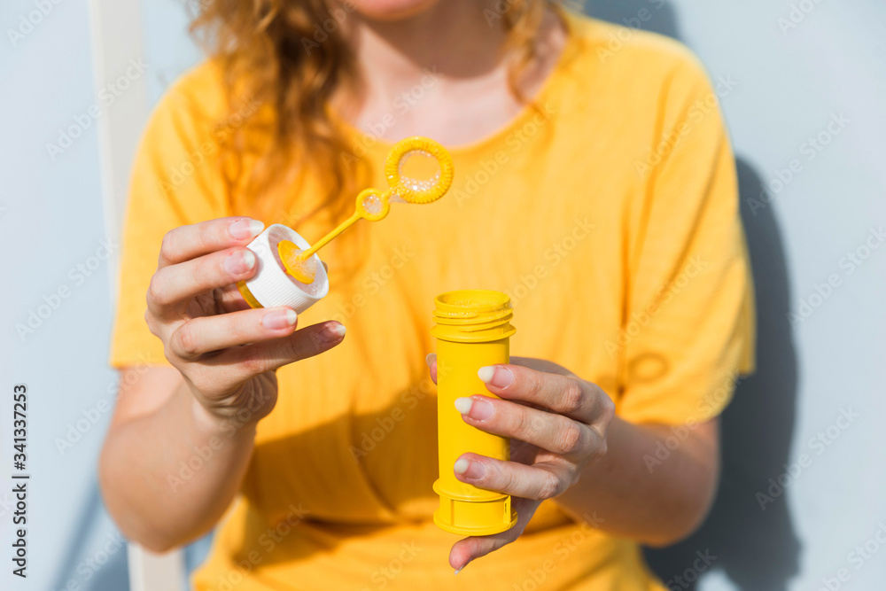 Fototapeta premium Close-up woman with bubbles maker wearing yellow dress