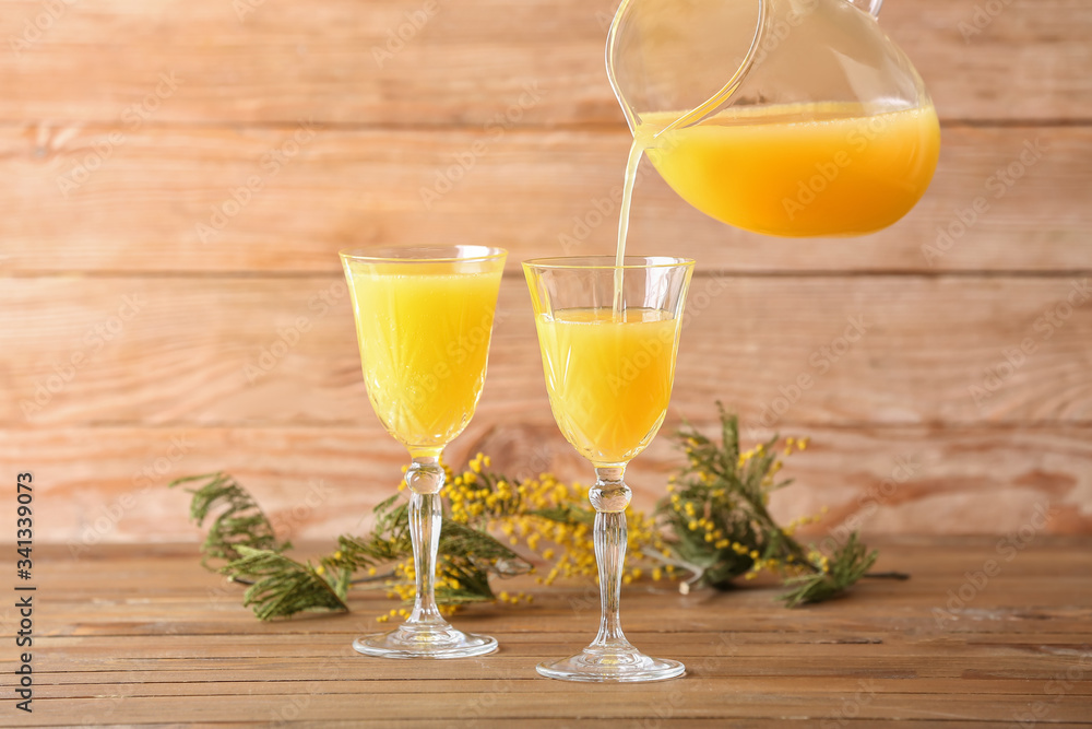 Preparing of tasty mimosa cocktail on wooden background