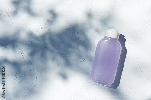 Bottle of micelar water or tonic, product for skincare beautyon textured concrete background with shadows. photo