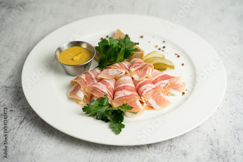 Plate with thinly sliced fat and mustard served with greens