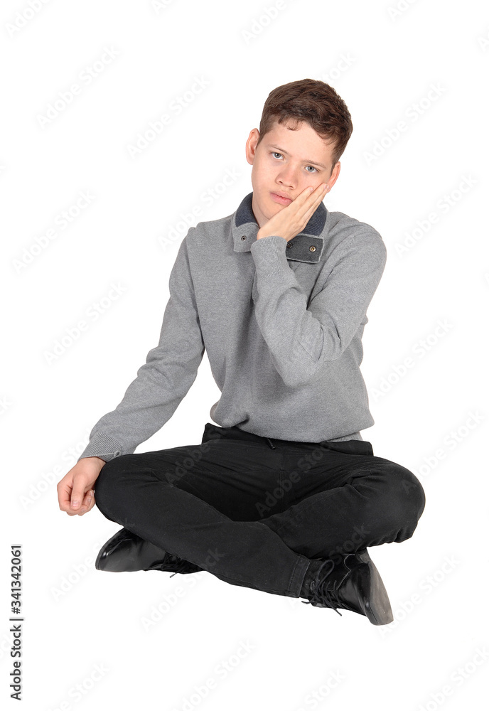 Teenage boy sitting on the floor with hand on his face Teenage boy sitting on the floor with hand on his face