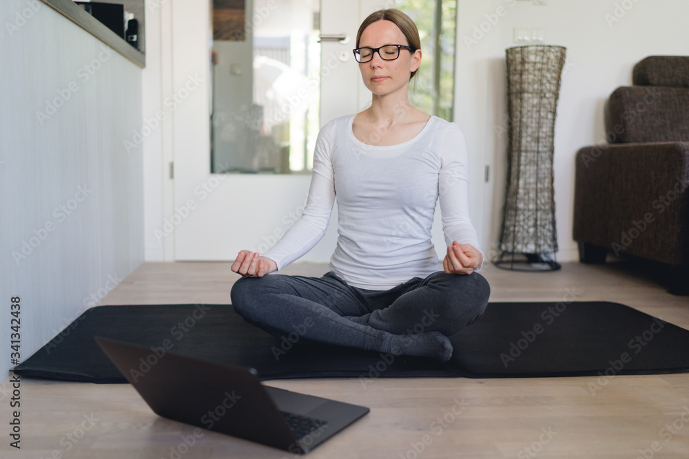 Frau meditiert zu Hause mittels online Kurs und tablet Frau meditiert zu Hause mittels online Kurs und tablet