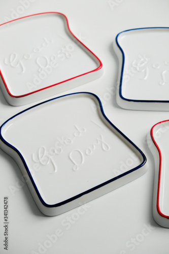 New ceramic plates in the form of fried toast with the inscription in English good day. Red and blue on a white isolated background. Top view.