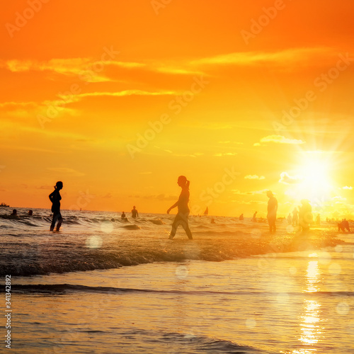 group of silhouetted people on public beach over orange colored sunset sky in Siesta key, Sarasota, Florida