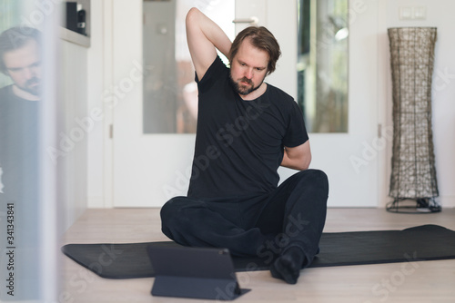 Mann macht Dehnungsübungen zu Hause mithilfe eines online-Kurses