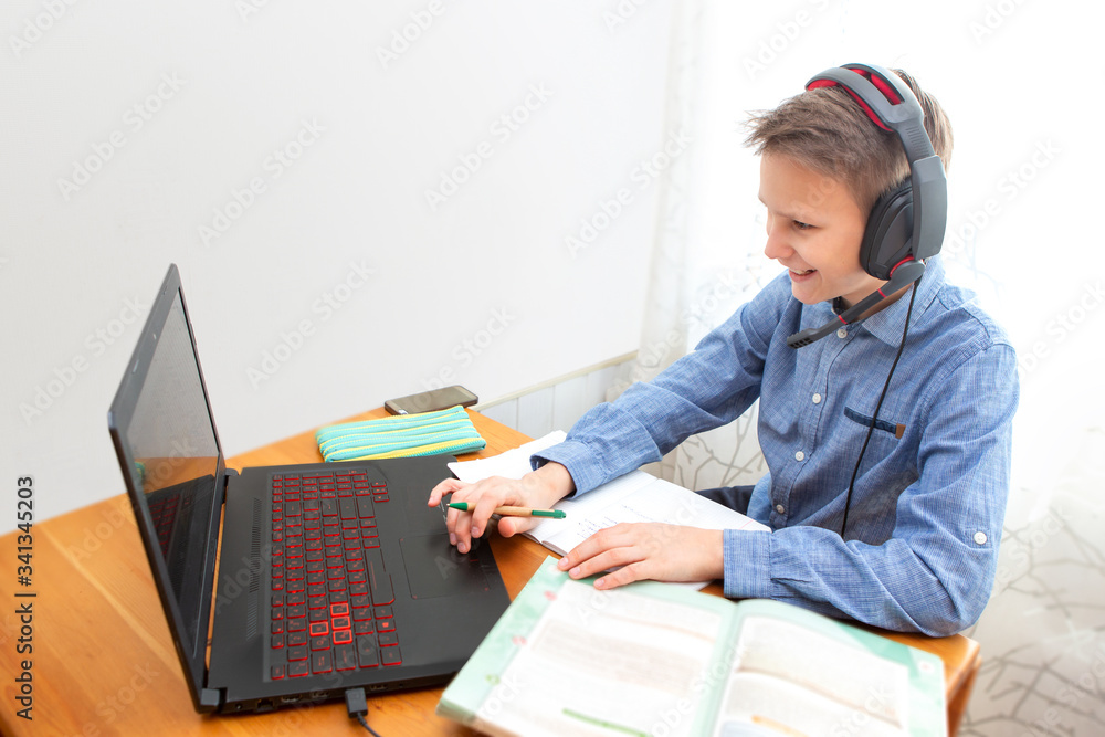 A teenager in headphones communicates with friends on a laptop. A teenager in headphones communicates with friends on a laptop.