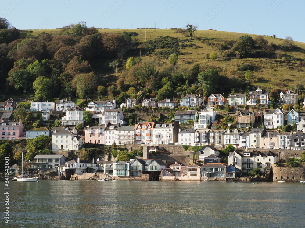  a hill in Kingswear , Devon seen across the River Dart in sunshine showing neat and colourful houses