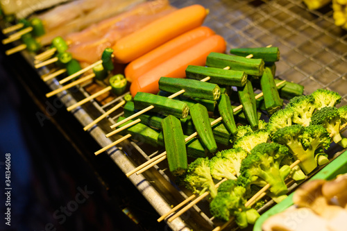 Broccoli and carrot on skewers for barbecue at food market in Thailand. Popular Asian food. Photo taken in low light at night