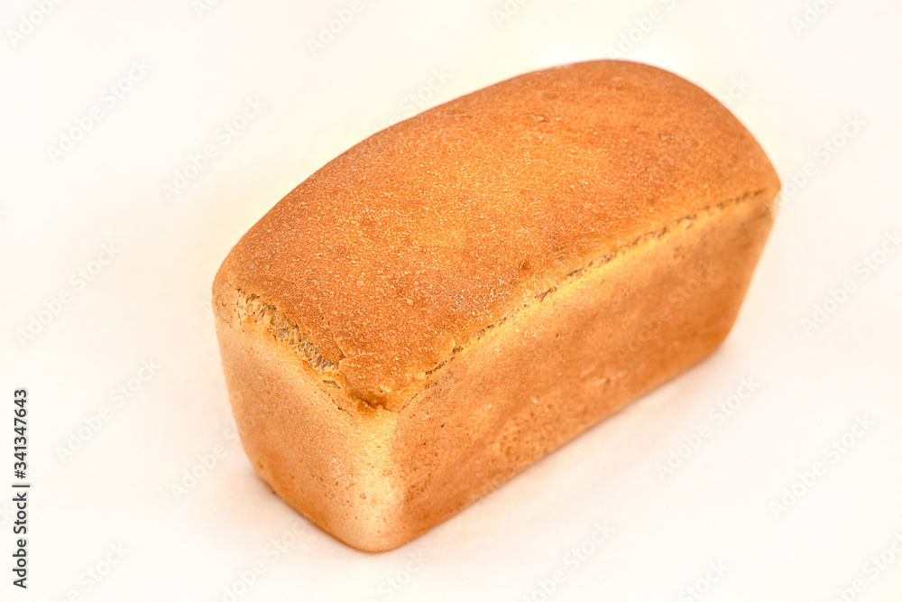 A loaf of white wheat bread. Closeup on a light background A loaf of white wheat bread. Closeup on a light background