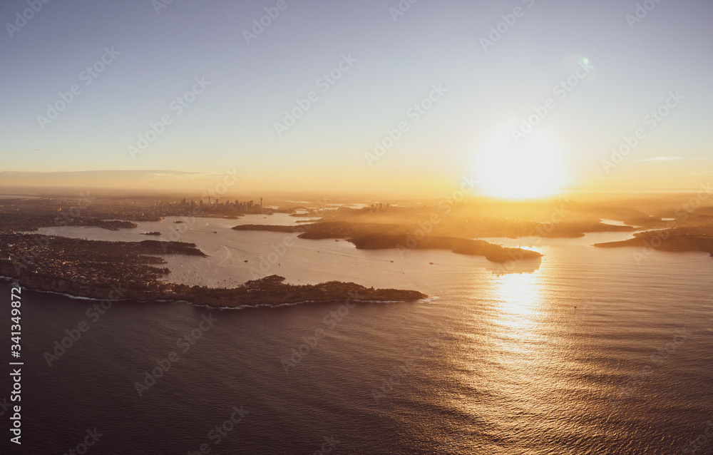 High resolution panoramic sunset aerial drone view of famous Sydney Harbour with the city centre in the background. South Head, a headland to the north of Watsons Bay suburb, in the foreground.