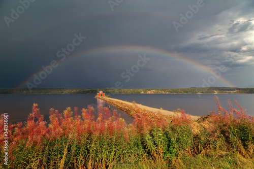 Rainbow in front of a dark, stormy sky over the Fornby pier at Siljansnäs, Siljan lake, Sweden.
