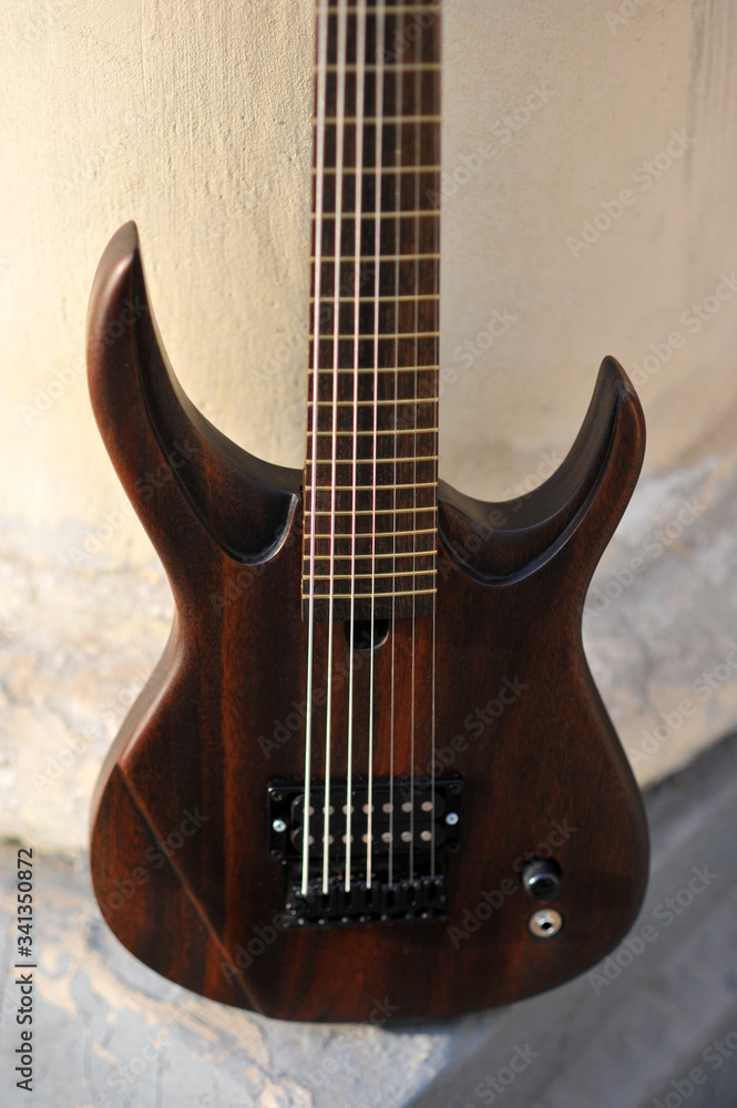 Seven-string electric guitar made of dark wood. Background for music and creativity.