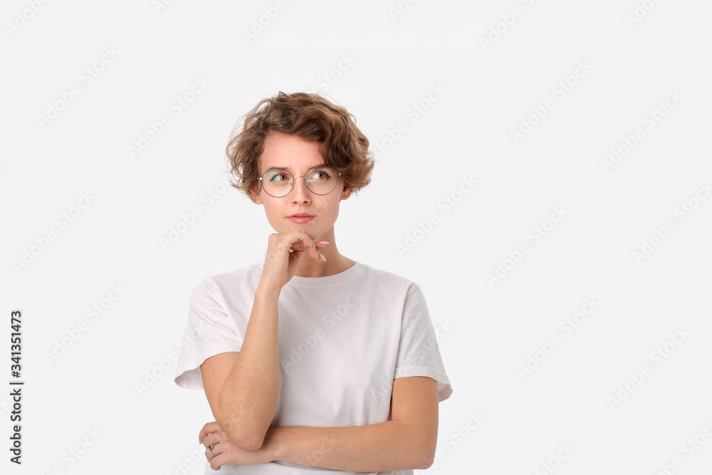 Thoughtful woman in a white shirt and eyeglasses looking at the copy space in a right upper corner Thoughtful woman in a white shirt and eyeglasses looking at the copy space in a right upper corner