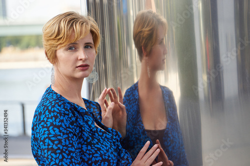 young woman with blue dress reflecting in glass front