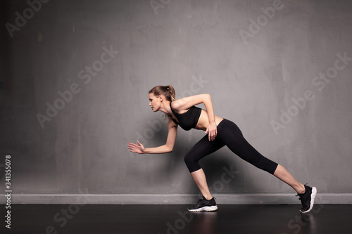 young woman doing exercise on grey background