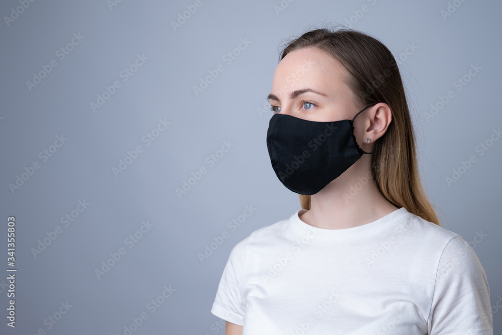 Woman in a black medical mask, isolated on a gray background Woman in a black medical mask, isolated on a gray background