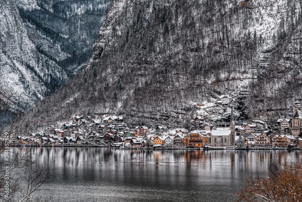 Distant view of beautiful village by lake at foot of snowy mountain Hallstatt in upper Austria