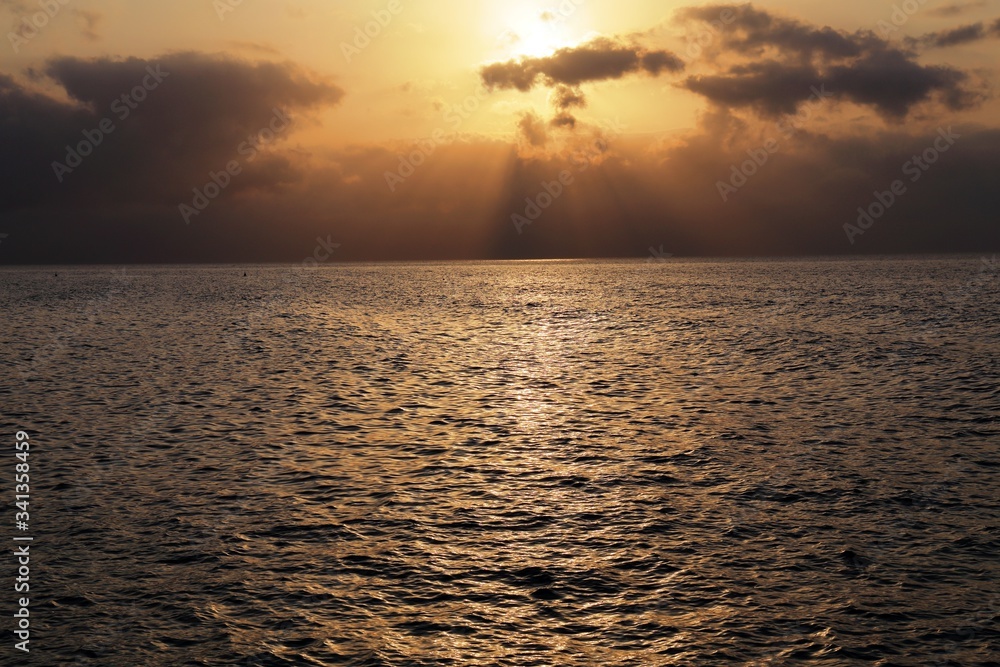 Obraz premium Luci del tramonto verso il mare all'isola d'Elba, Italia, con bellissimi colori e raggi di sole tra le nuvole e riflessi sull'acqua