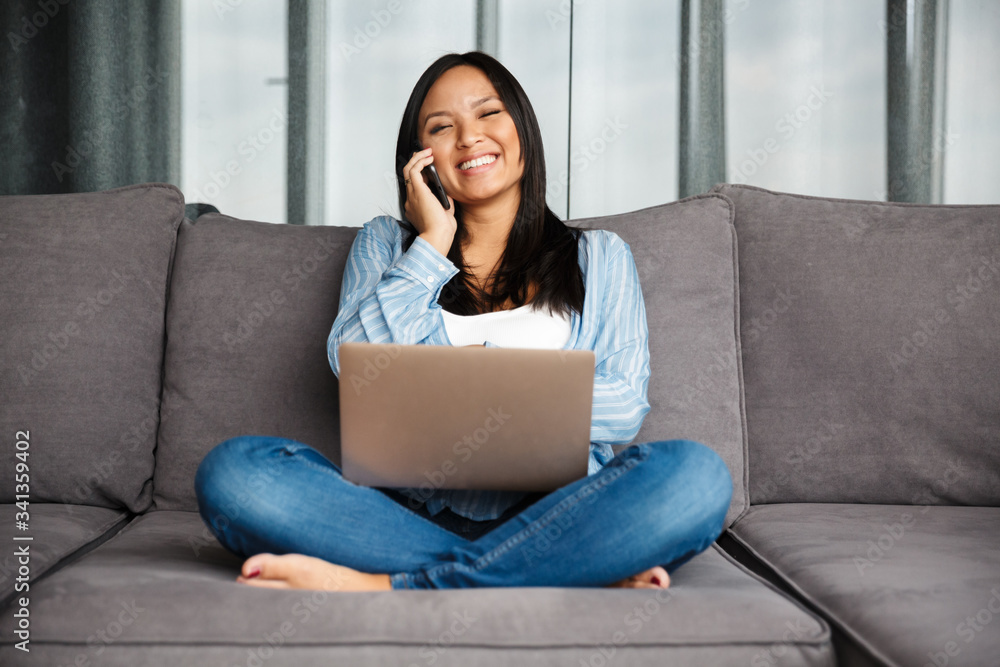 Photo of smiling pregnant woman talking on cellphone and using laptop Photo of smiling pregnant woman talking on cellphone and using laptop