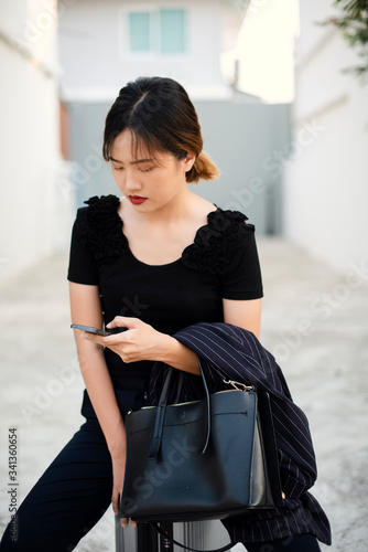 Portrait of business woman standing on the street with smartphone in her hand